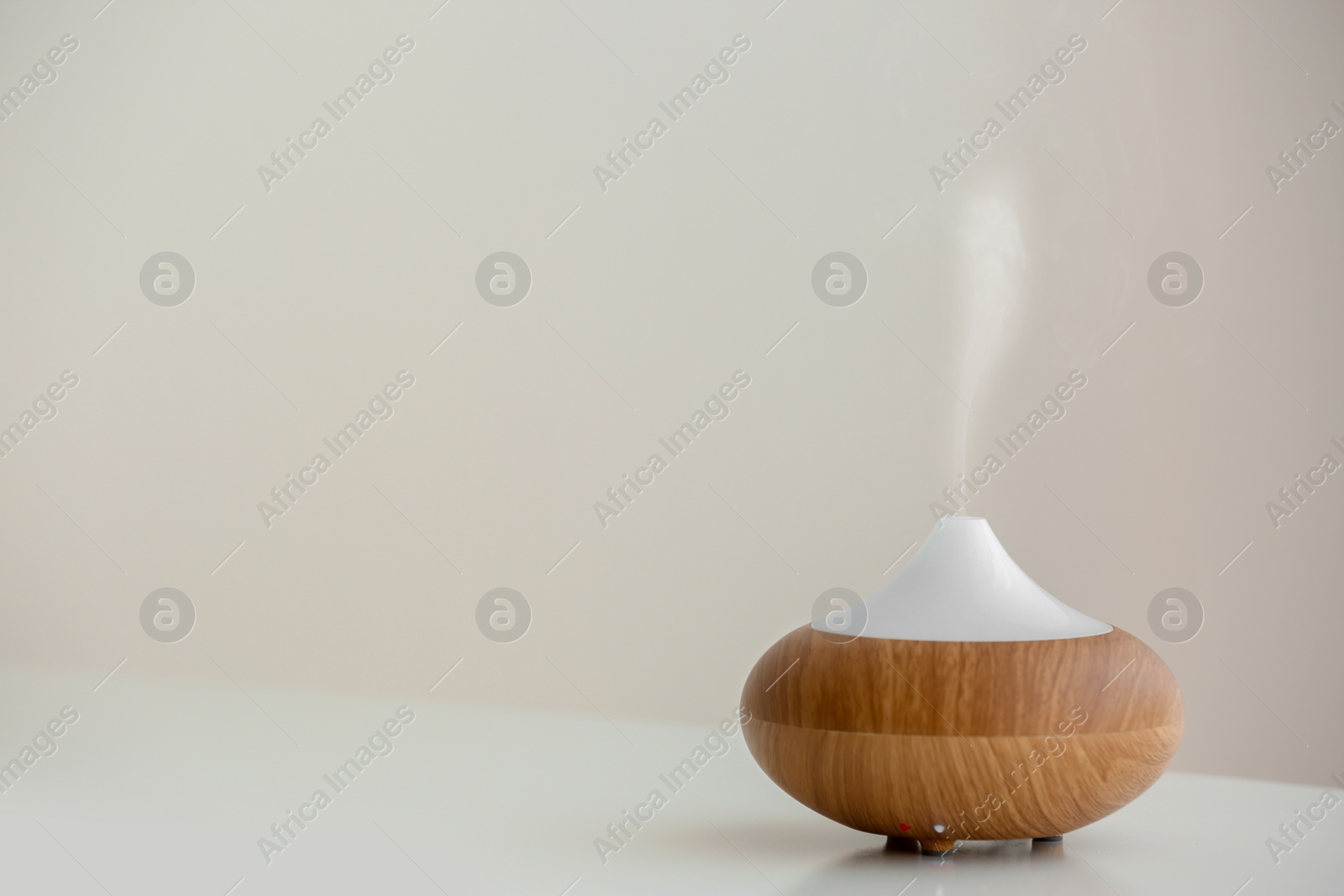 Photo of Aroma oil diffuser lamp on table against light background