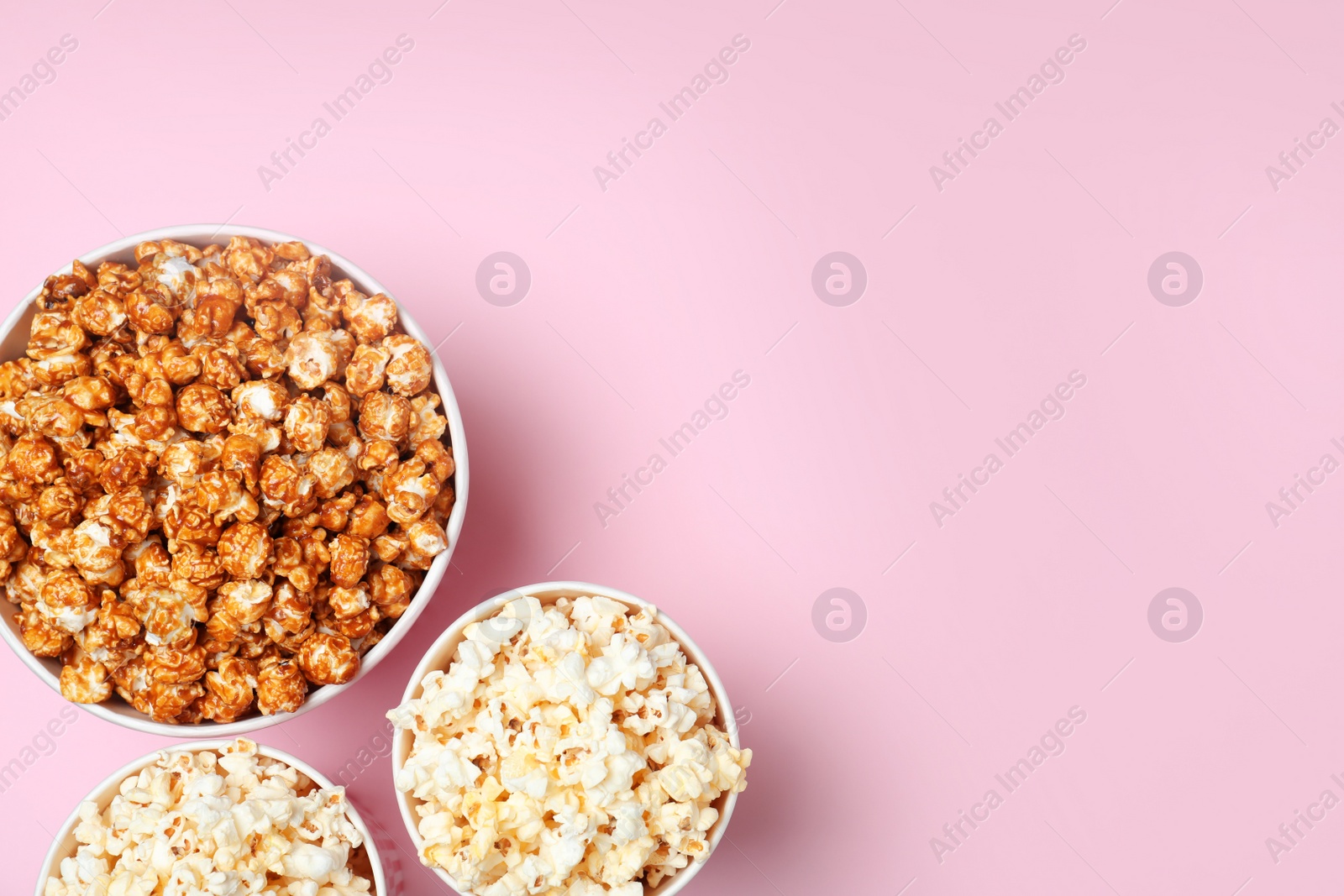 Photo of Different kinds of popcorn on color background, top view. Space for text