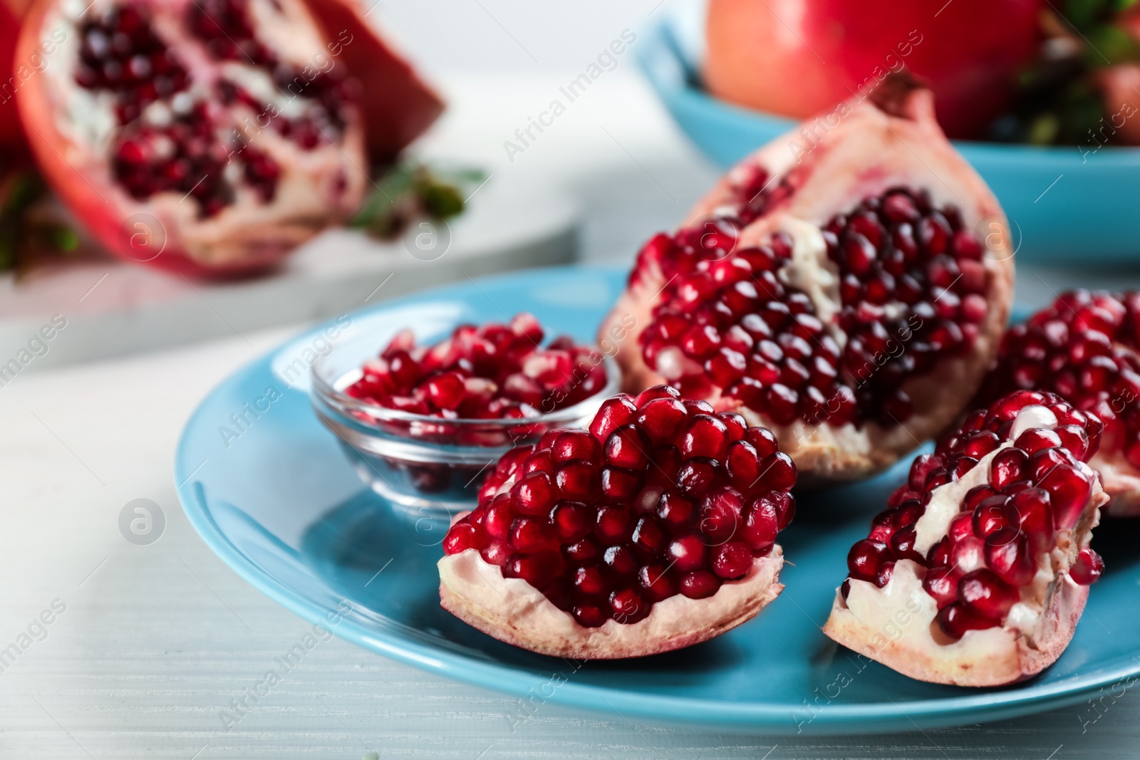 Photo of Delicious ripe pomegranates on white wooden table, closeup