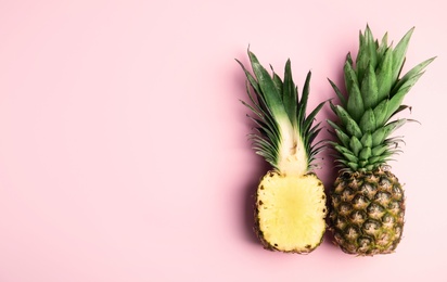 Photo of Whole and cut pineapples on pink background, flat lay. Space for text