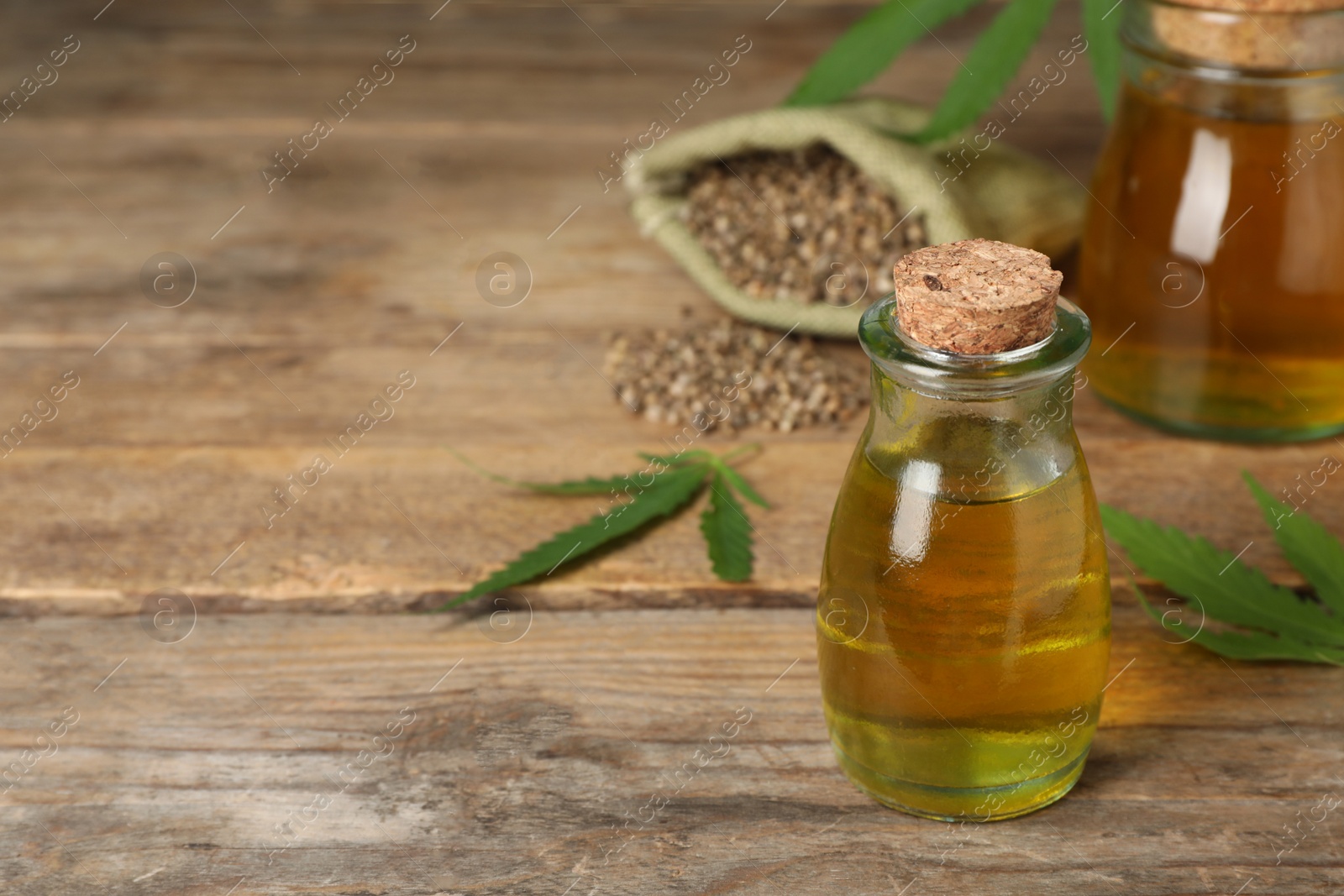 Photo of Bottle of hemp oil on wooden table, space for text