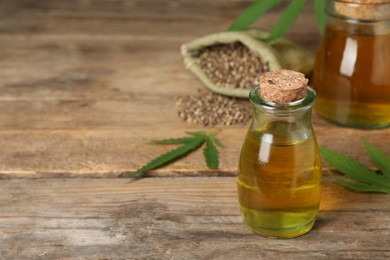 Photo of Bottle of hemp oil on wooden table, space for text