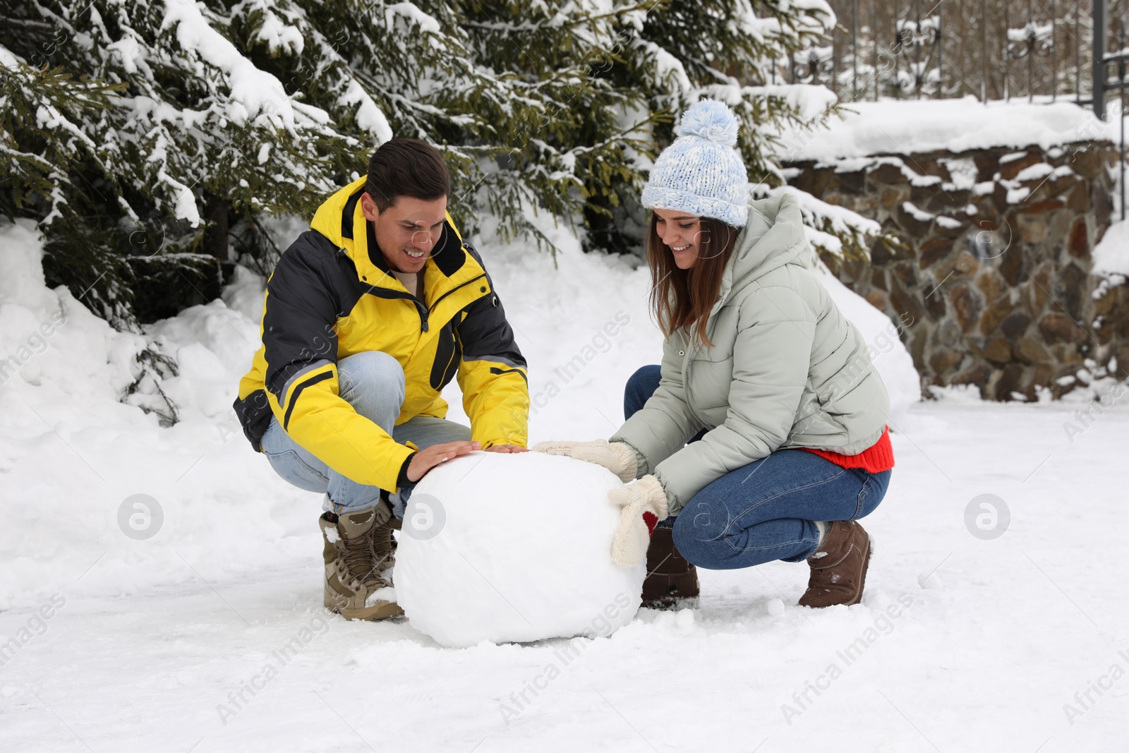 Photo of Happy couple making ball for snowman outdoors. Winter vacation