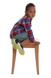 Photo of Little African-American boy climbing up stool on white background. Danger at home