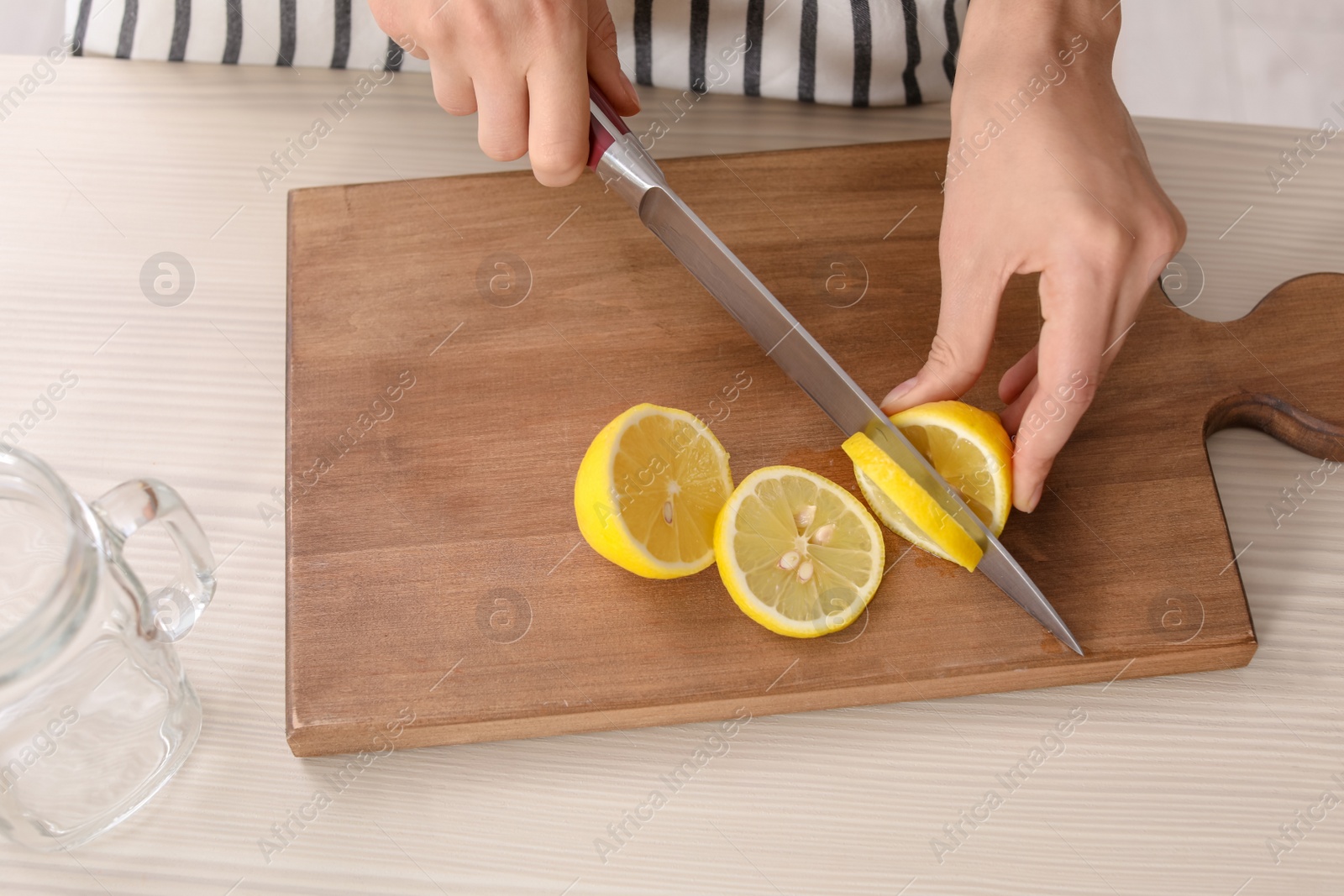 Photo of Young woman preparing lemonade on table, closeup. Natural detox drink