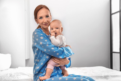 Photo of Young woman with her little baby resting after breast feeding in bedroom