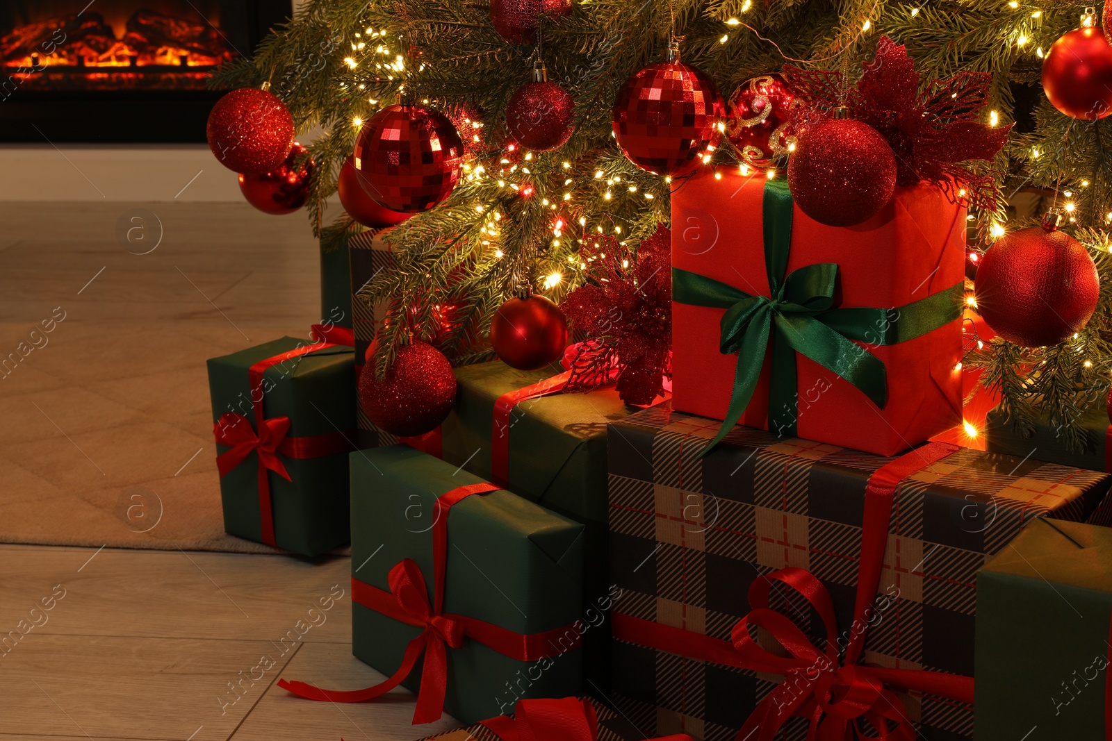 Photo of Many gift boxes under decorated Christmas tree indoors