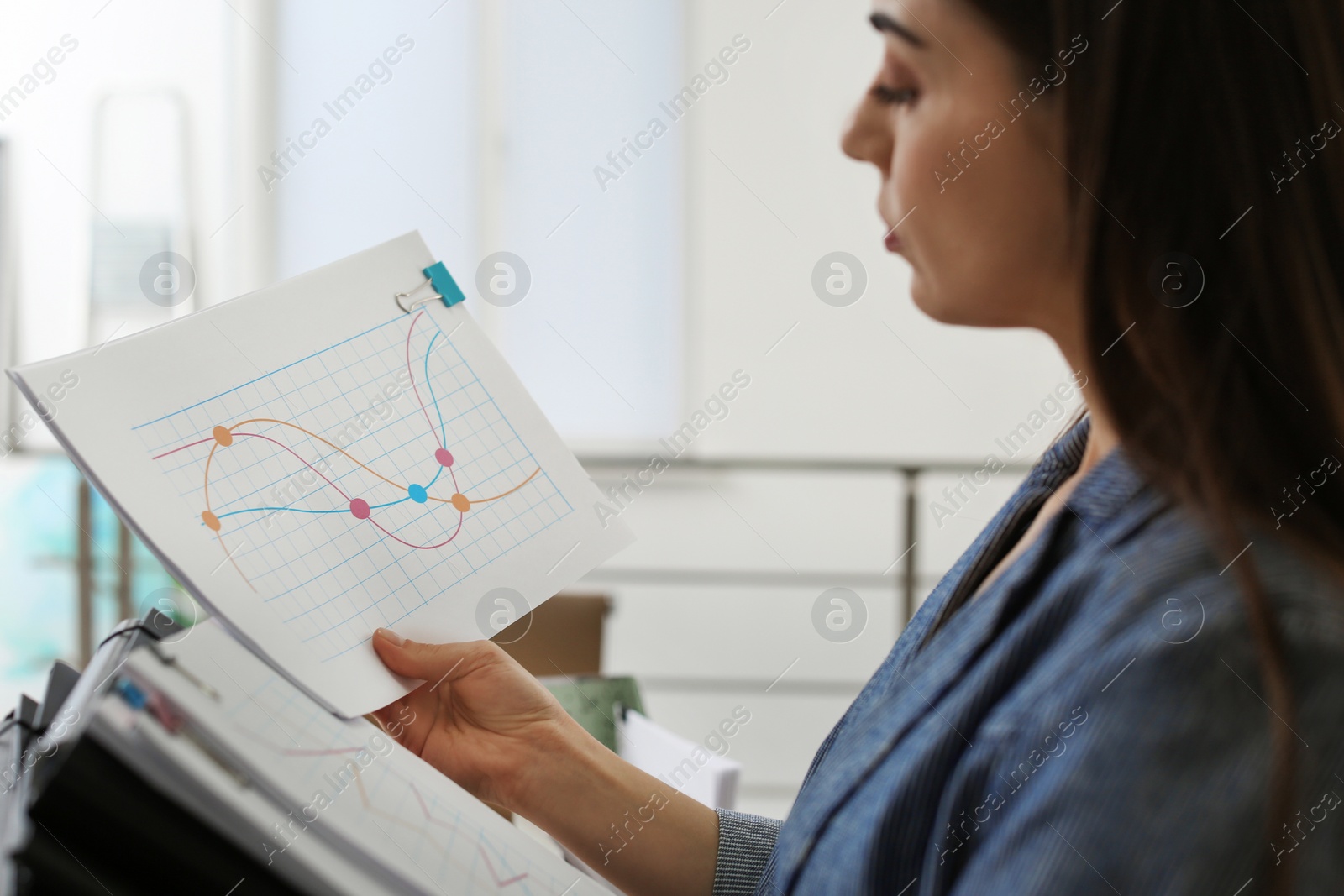 Photo of Young woman working with documents in office