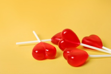 Photo of Sweet heart shaped lollipops on yellow background, closeup view with space for text. Valentine's day celebration