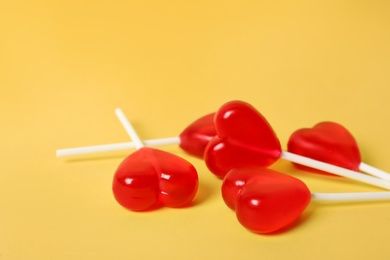 Sweet heart shaped lollipops on yellow background, closeup view with space for text. Valentine's day celebration