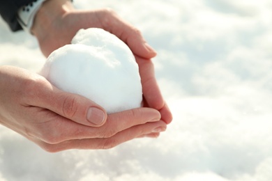 Photo of Woman holding heart made of snow outdoors, closeup. Space for text