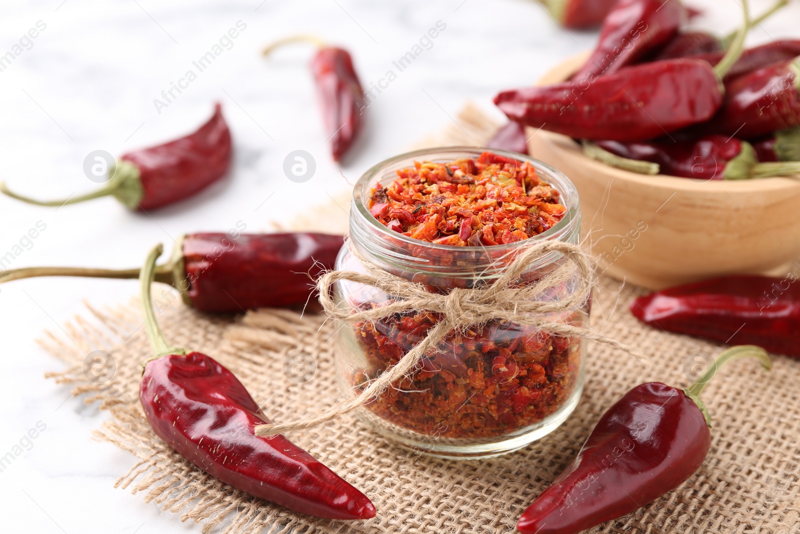 Photo of Chili pepper flakes and pods on white table