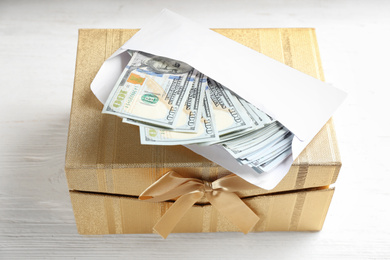 Gift box with dollar bills on white wooden table