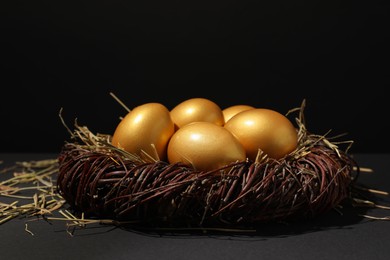 Shiny golden eggs in nest on black background