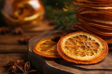 Photo of Dry orange slices and anise stars on wooden table, closeup. Space for text