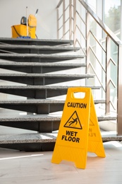 Photo of Safety sign with phrase Caution wet floor near stairs. Cleaning service