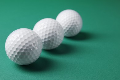 Photo of Three golf balls on green background, closeup. Space for text