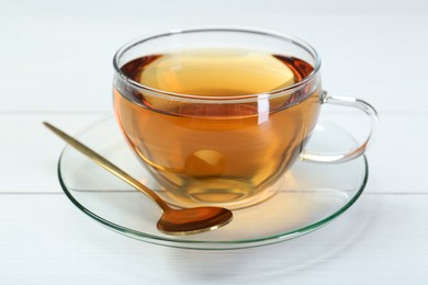 Glass cup of tea and spoon on white table