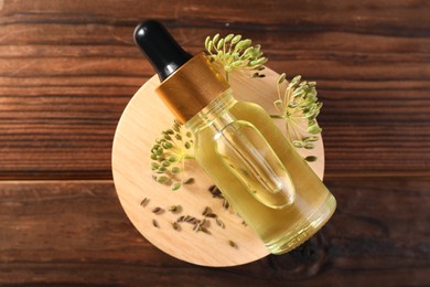 Bottle of essential oil, seeds and fresh dill on wooden table, top view