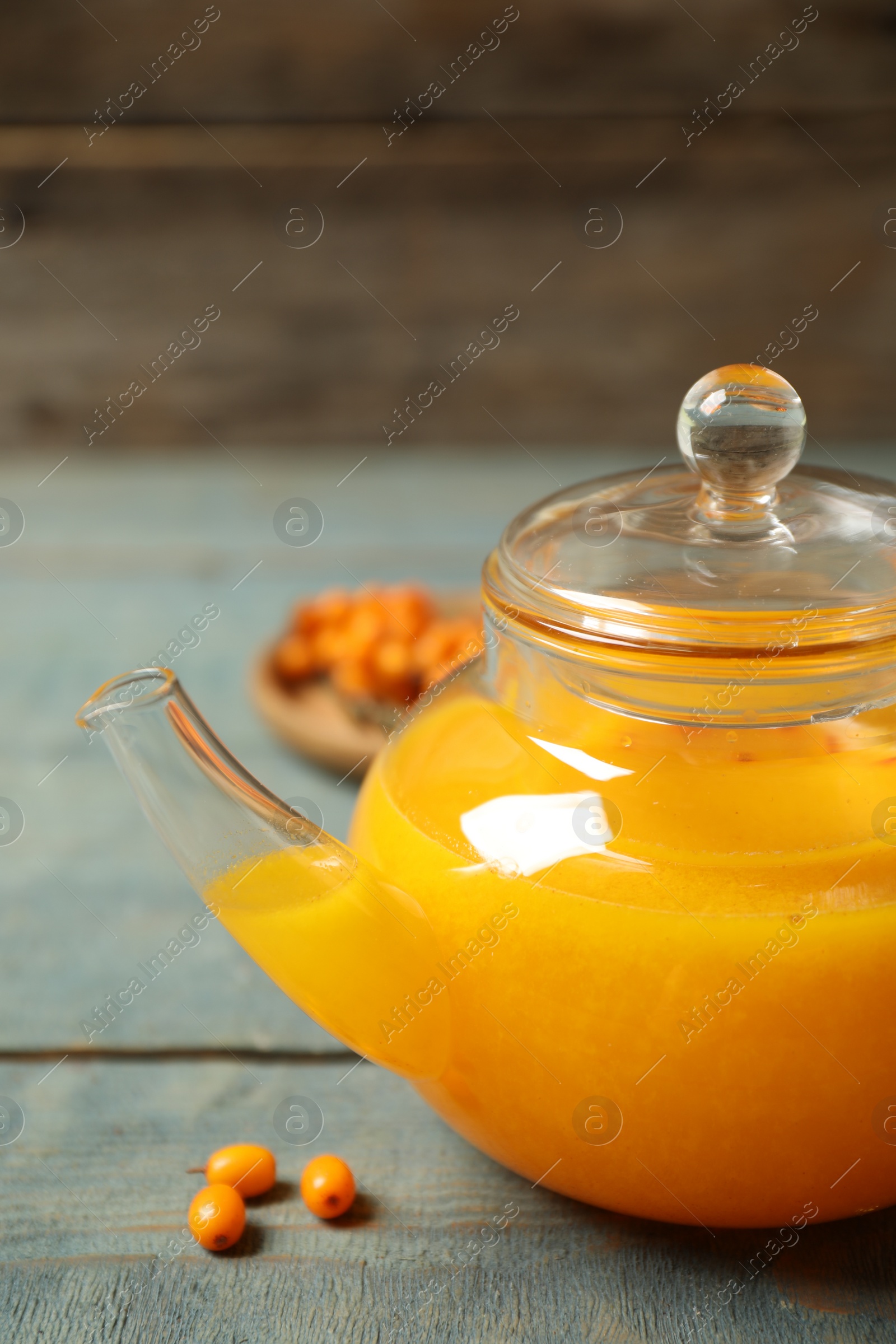 Photo of Delicious sea buckthorn tea on blue wooden table, closeup