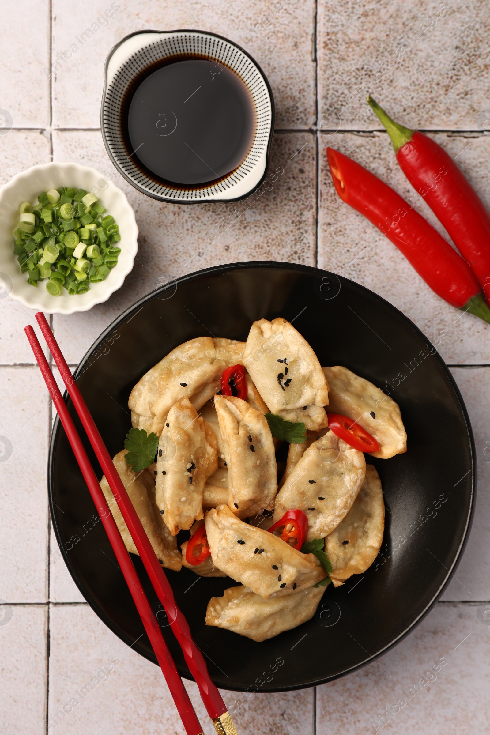 Photo of Delicious gyoza (asian dumplings) served on light tiled table, flat lay