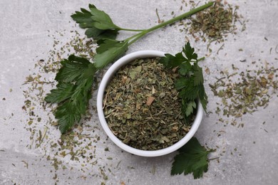 Photo of Dried parsley and fresh leaves on light grey table, flat lay