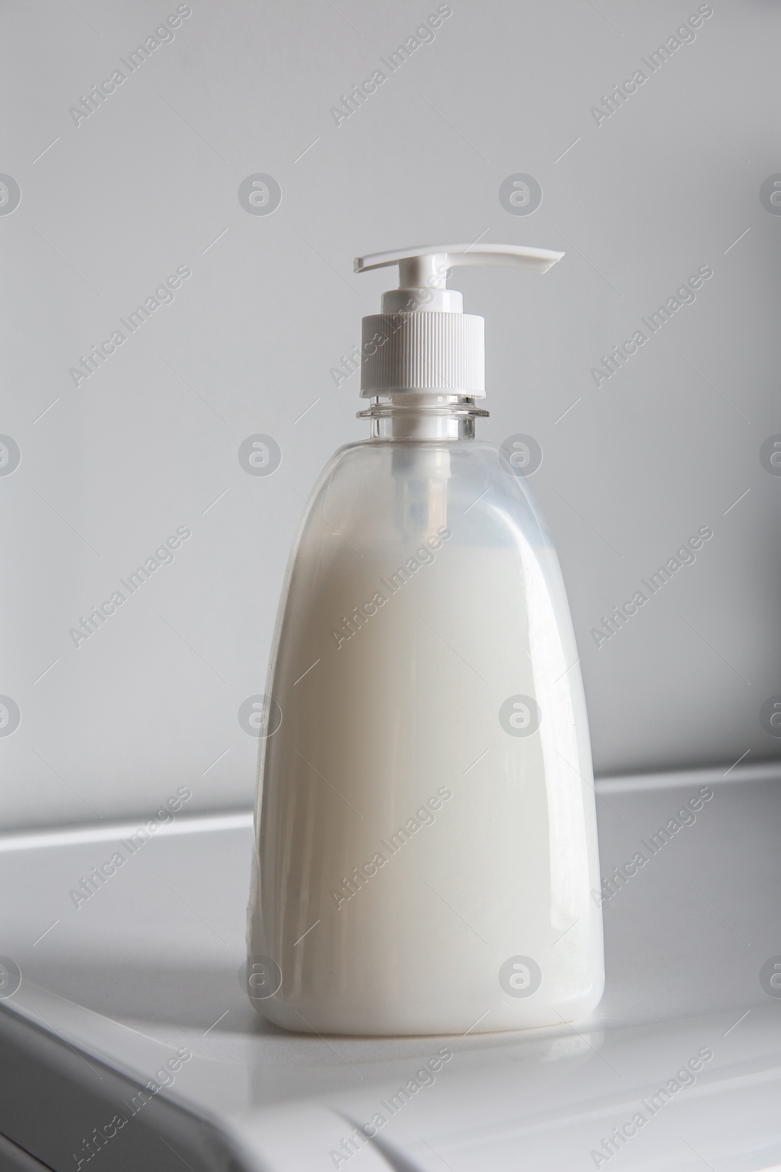 Photo of Bottle of liquid soap on table against light background