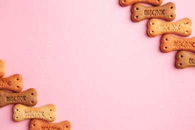 Photo of Bone shaped dog cookies on pink background, flat lay. Space for text