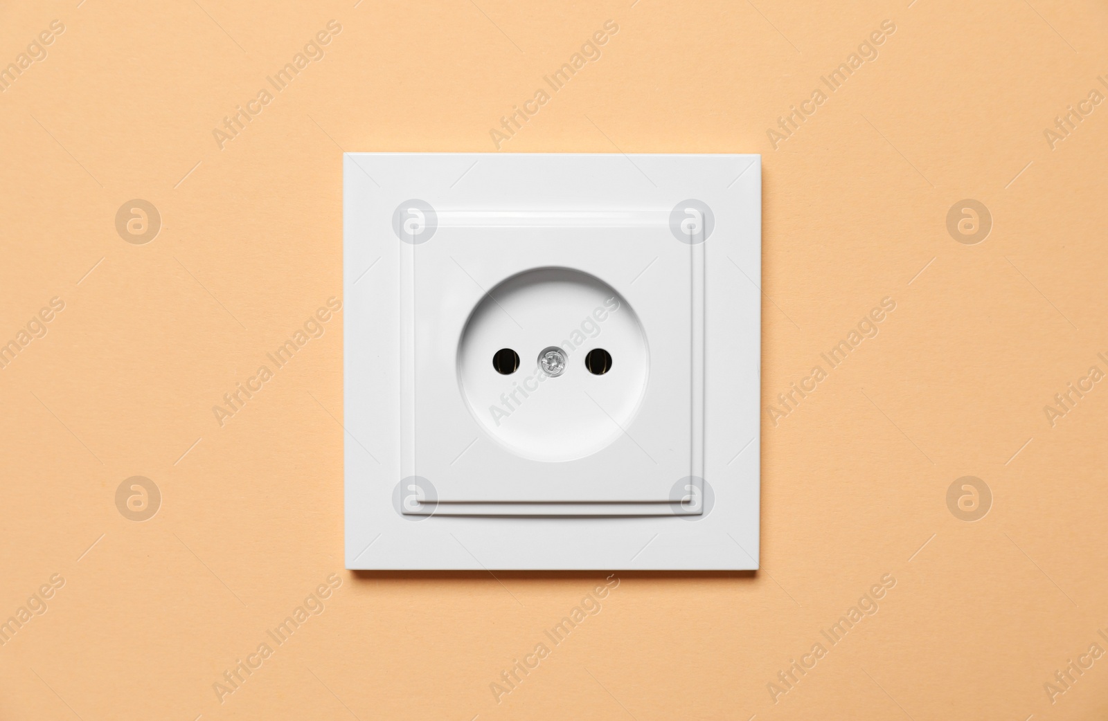 Photo of Power socket on pale orange wall. Electrical supply
