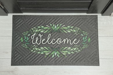 Photo of Doormat with word Welcome on white floor near entrance, top view