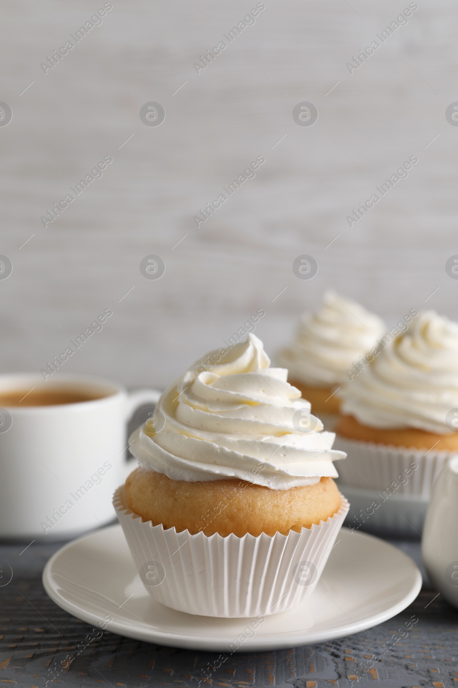 Photo of Delicious cupcake with cream on grey wooden table. Space for text