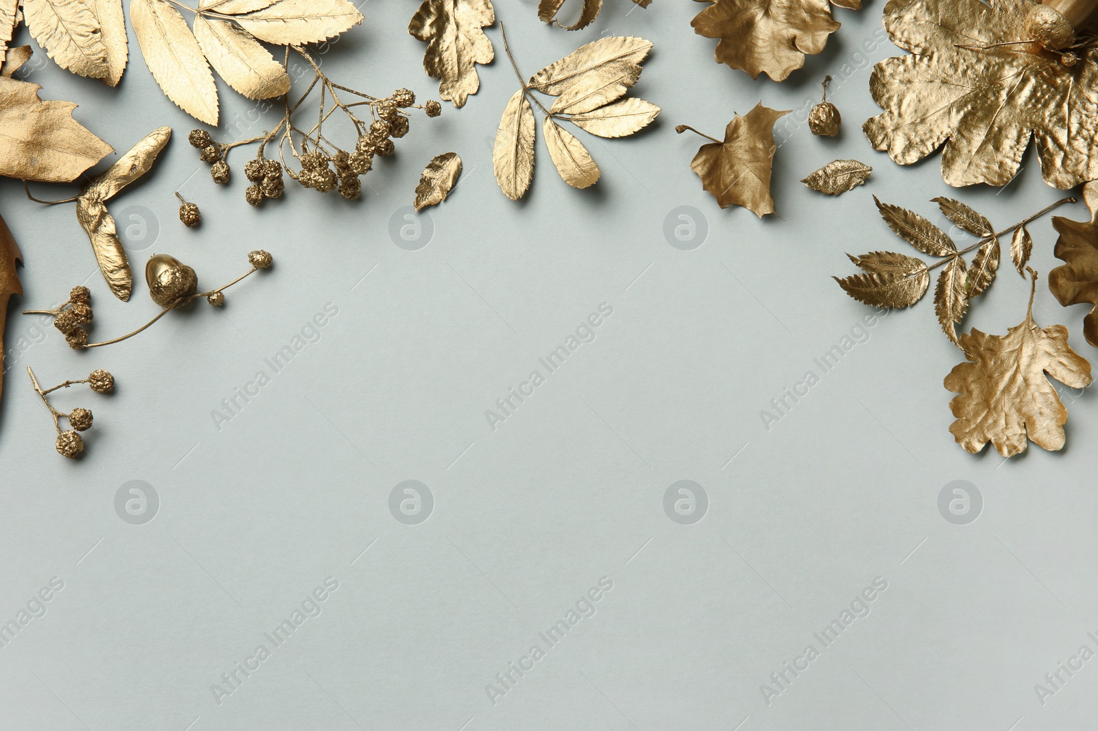 Photo of Beautiful golden leaves, berries and acorns on light grey background, flat lay with space for text. Autumn decor
