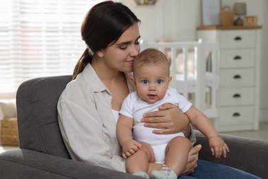 Photo of Happy young mother with her baby in armchair at home