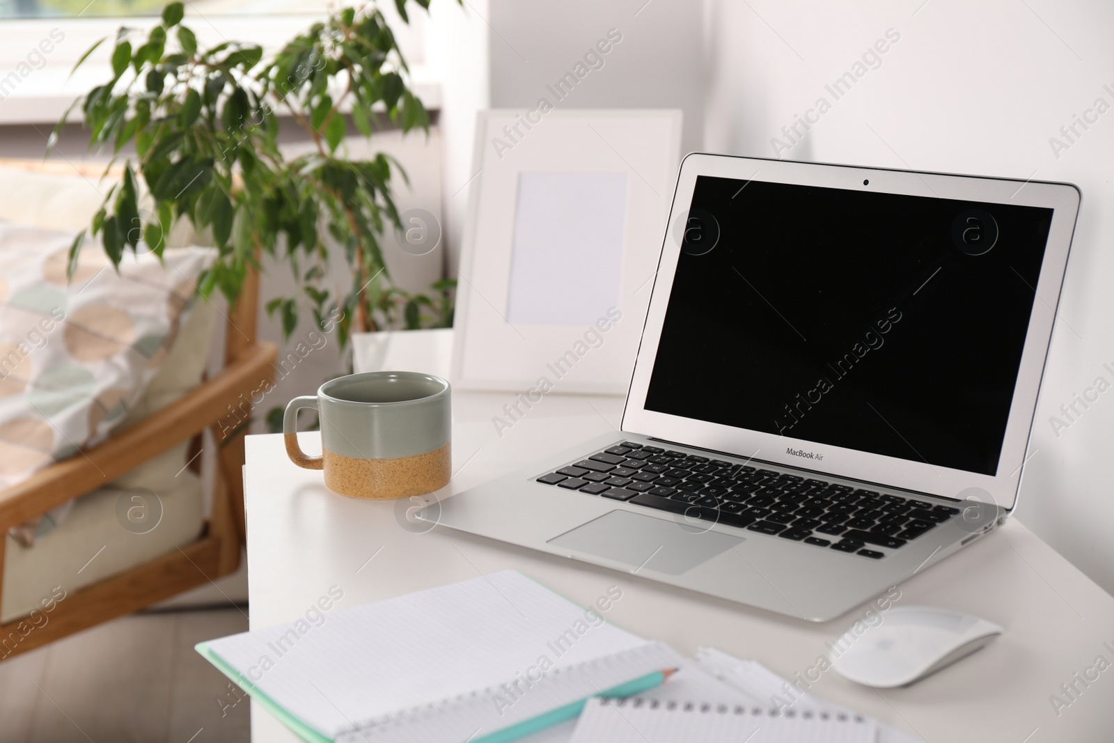 Photo of Beautiful workplace with laptop on white wooden table in room