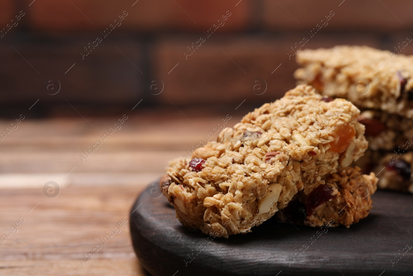 Photo of Tasty granola bars on wooden table, closeup. Space for text