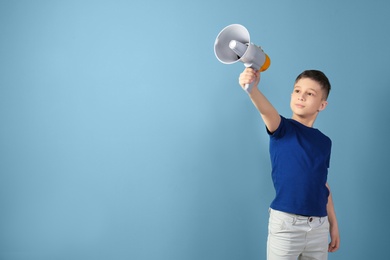 Cute little boy with megaphone on color background