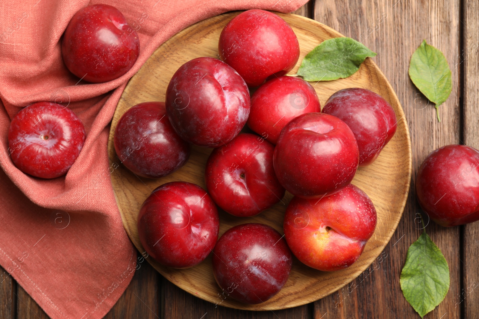 Photo of Delicious ripe plums on wooden table, flat lay