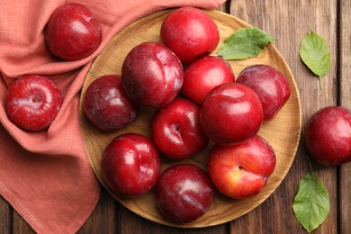 Photo of Delicious ripe plums on wooden table, flat lay