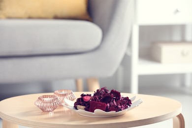 Aromatic potpourri of dried flowers and candles on coffee table indoors