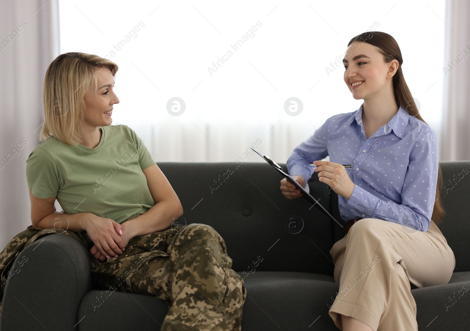 Photo of Psychotherapist working with military woman on sofa in office