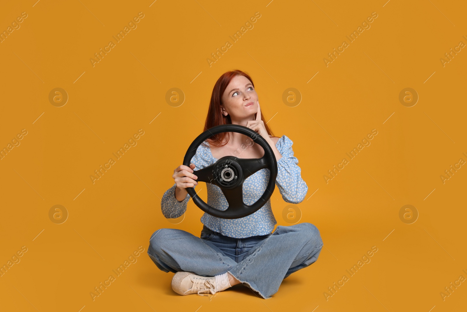 Photo of Young woman with steering wheel on yellow background
