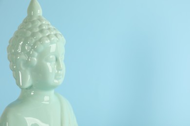 Photo of Beautiful ceramic Buddha sculpture on light blue background. Space for text