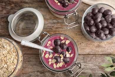 Photo of Flat lay composition with jar of tasty acai smoothie on wooden table