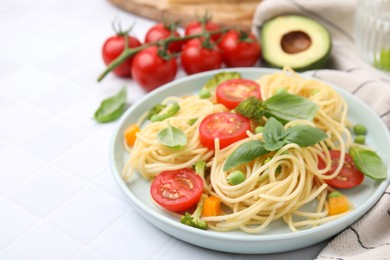 Photo of Plate of delicious pasta primavera and ingredients on white table, closeup