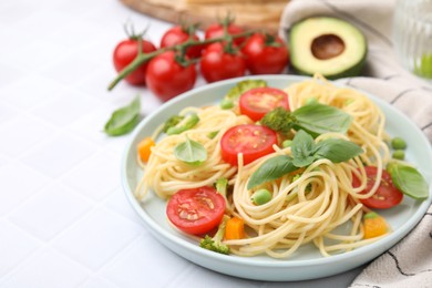 Plate of delicious pasta primavera and ingredients on white table, closeup