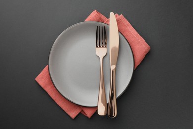 Clean plate, cutlery and napkin on grey table, top view