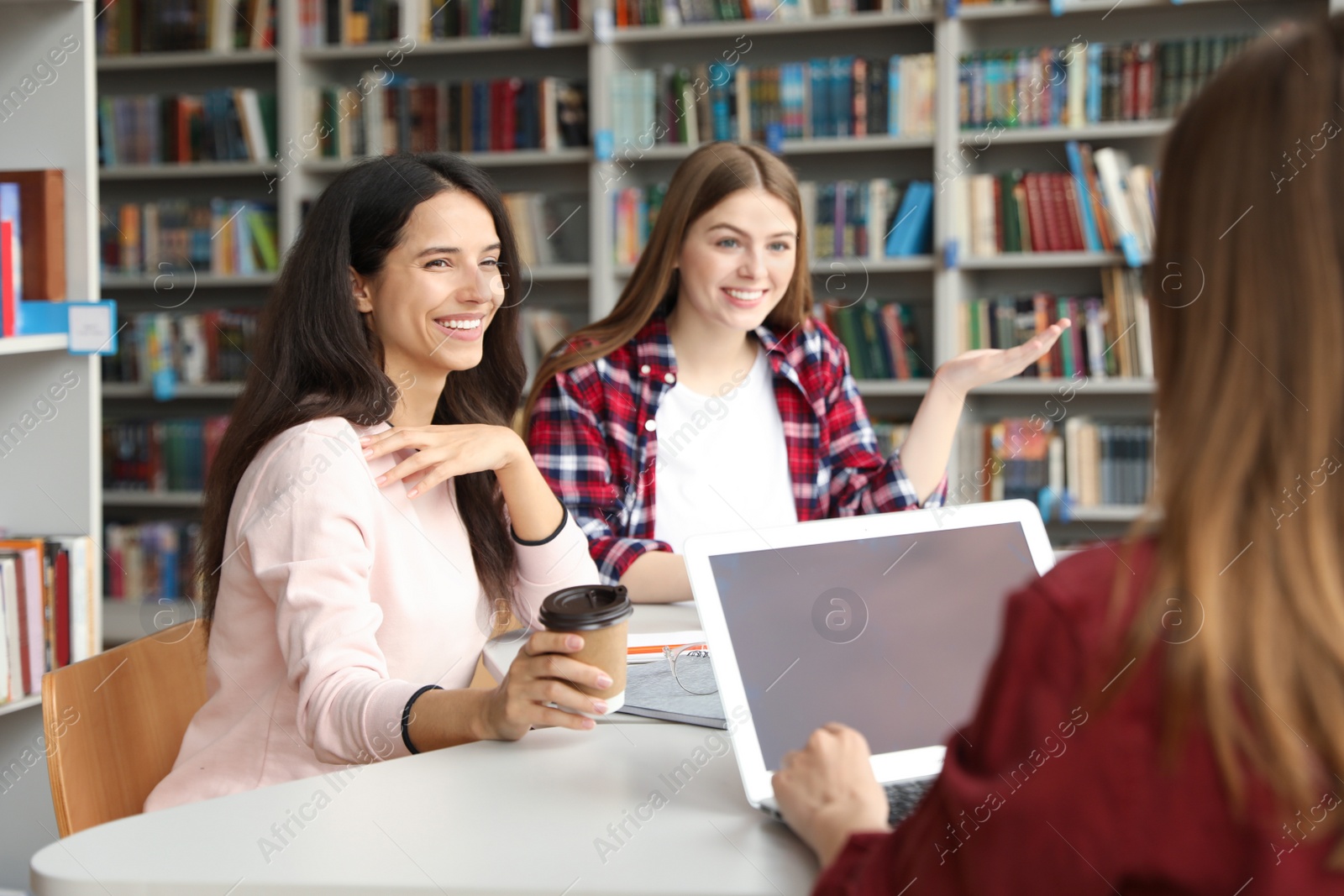 Photo of Young people discussing group project at table in library