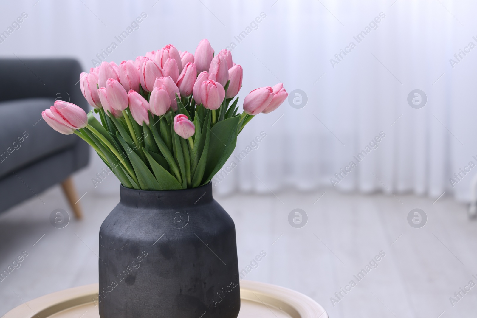 Photo of Bouquet of beautiful pink tulips in vase on table indoors, space for text