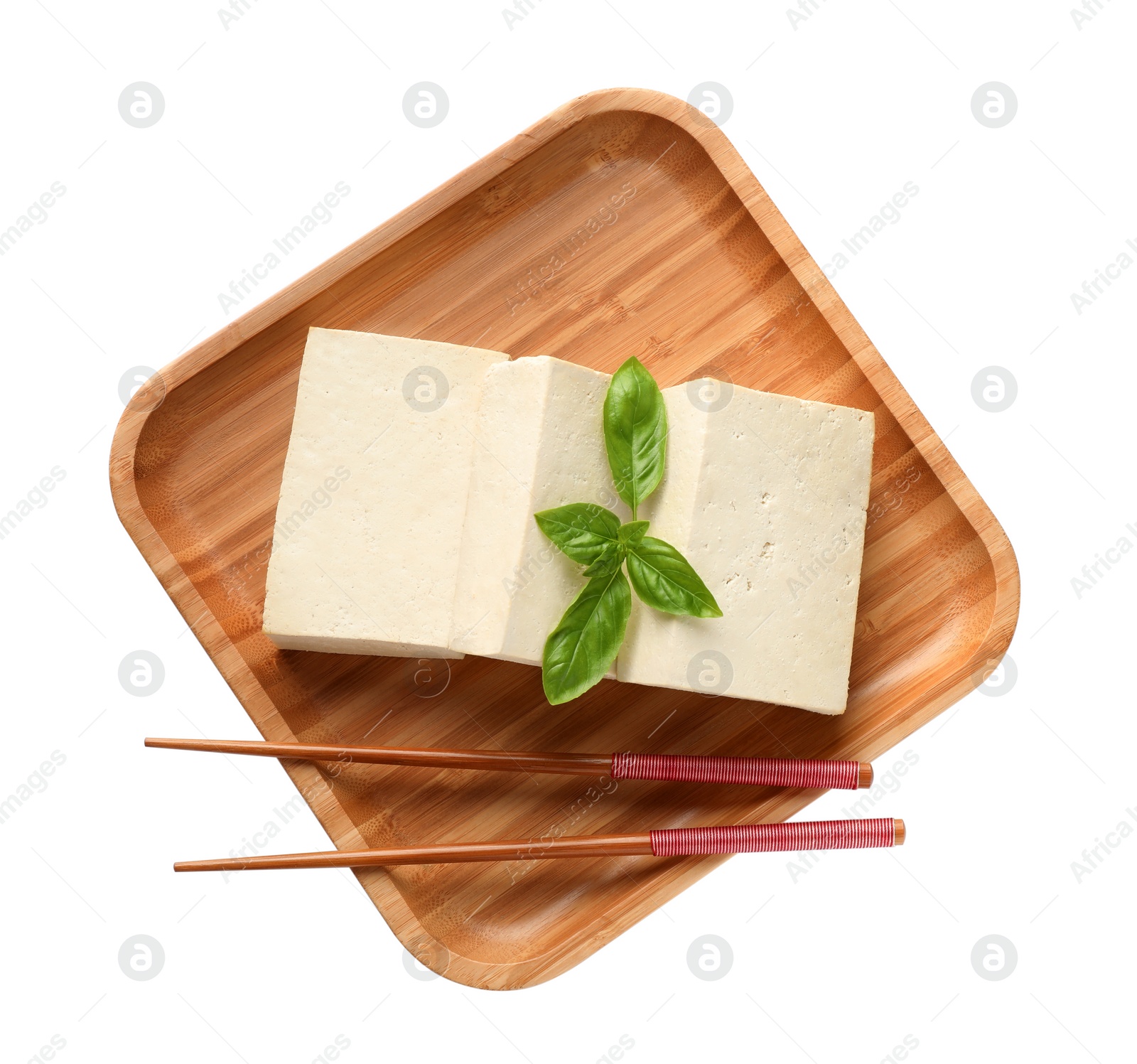 Photo of Wooden plate with delicious raw tofu, basil and chopsticks on white background, top view