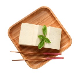 Photo of Wooden plate with delicious raw tofu, basil and chopsticks on white background, top view